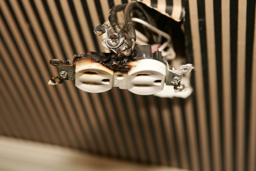 A damaged and burnt electrical outlet with signs of a short circuit.